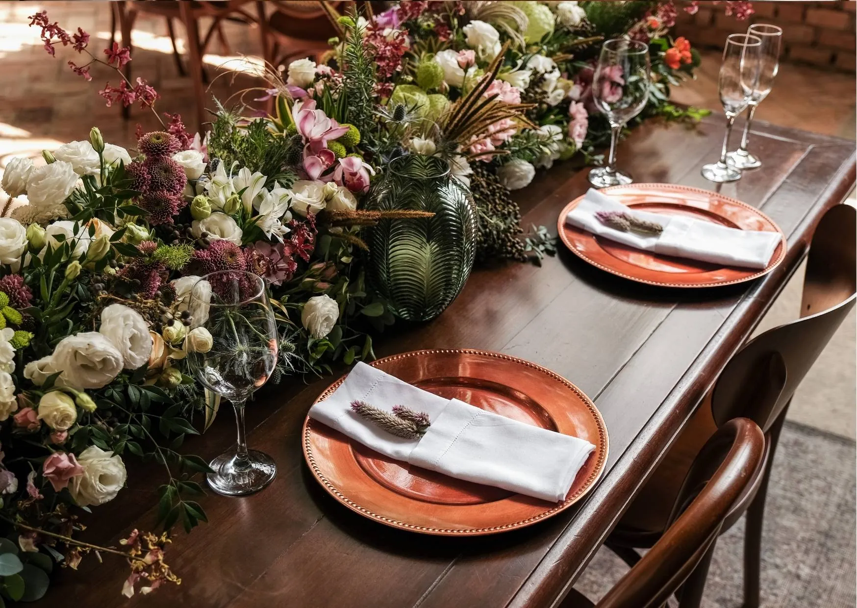 Mesa posta com pratos de cobre, flores e cardápio